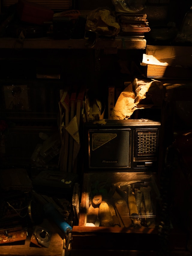A warmly lit vintage radio and shelves in a dark room
